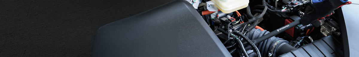 Black textured vehicle console panel beside exposed wiring and mechanical components, showing a secure fitted assembly