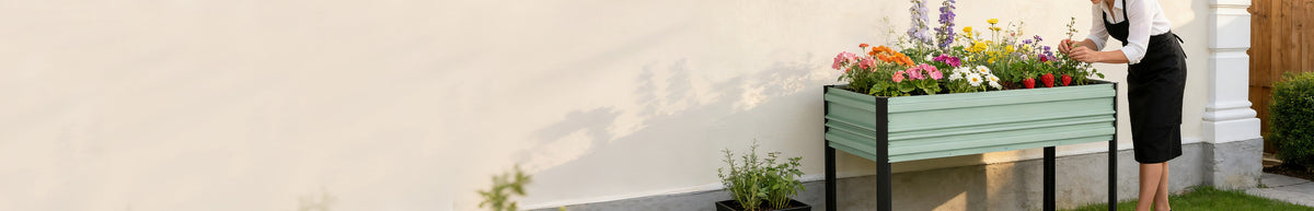 Raised green garden planter filled with flowering plants beside a person on a patio