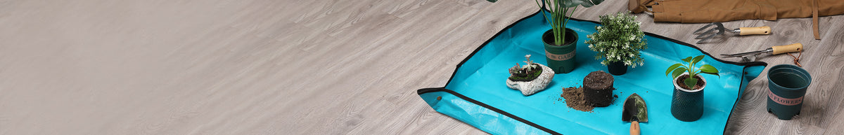 Turquoise outdoor rug with potted plants and gardening tools arranged on its textured surface