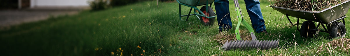 Garden rake with a long green handle beside a wheelbarrow on grass, showing a worker tending a lawn