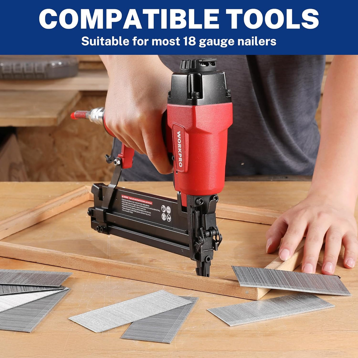 Silver brad nails laid out on a wooden board while a pneumatic nailer fires