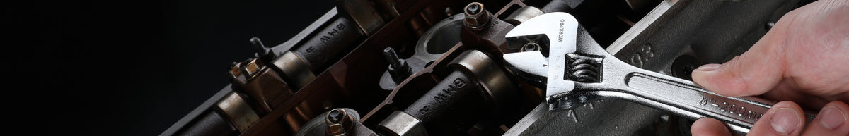 Hands use a silver adjustable wrench on a black metal pipe assembly, showing visible innovation in mechanical repair