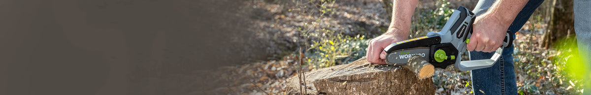 Person using a cordless hedge trimmer to cut a garden hedge beside a gravel path