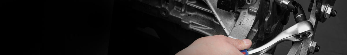 Hand using a wrench to tighten a fastener on a dark metal mechanical assembly