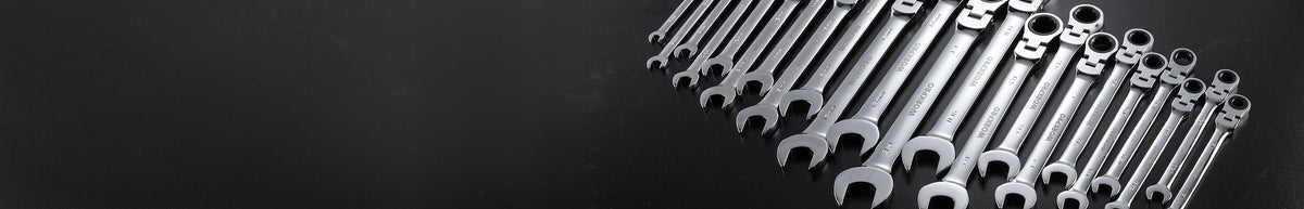Set of silver combination wrenches arranged diagonally on a dark surface, showing open and ring ends