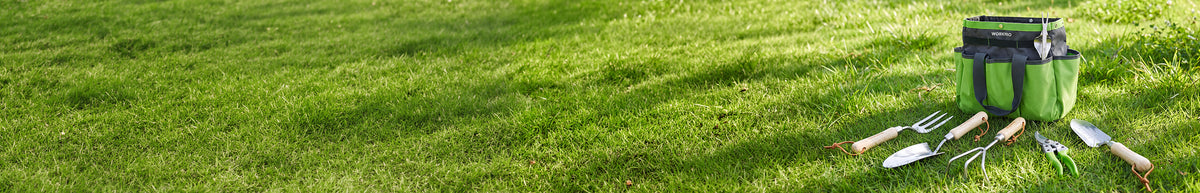 Lawn care tools including a trimmer, shears, rake, and green storage bags arranged on grass